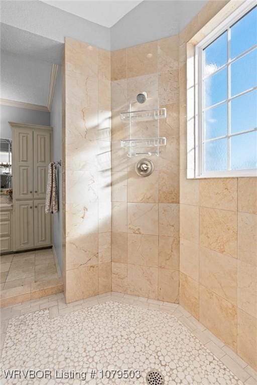 bathroom with tiled shower and crown molding