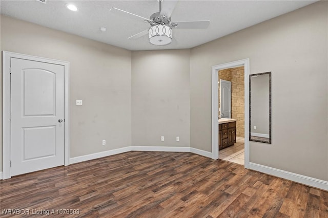 spare room featuring baseboards, wood finished floors, and ceiling fan