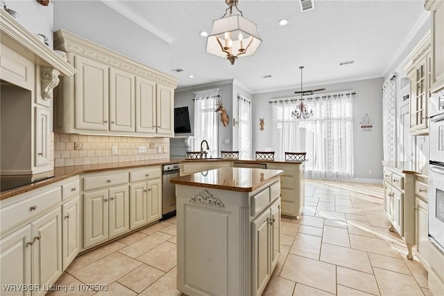 kitchen featuring ornamental molding, a peninsula, cream cabinets, a notable chandelier, and a sink