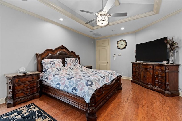 bedroom featuring a raised ceiling, crown molding, and wood finished floors