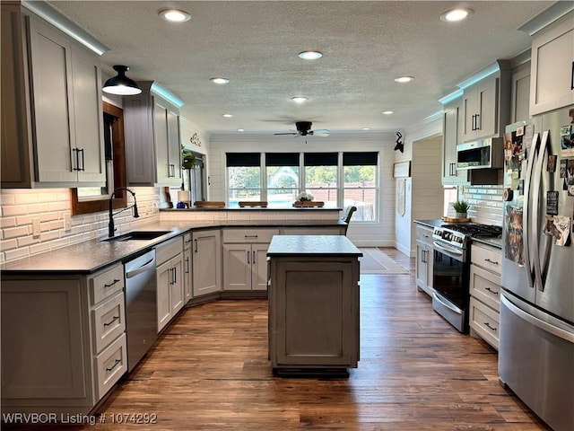 kitchen with ceiling fan, sink, stainless steel appliances, dark hardwood / wood-style floors, and kitchen peninsula