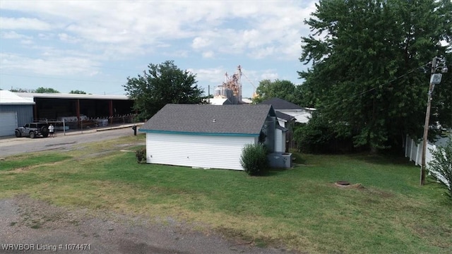 view of side of property with an outbuilding, a carport, and a lawn