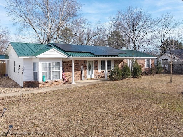 single story home with a front yard, solar panels, and covered porch