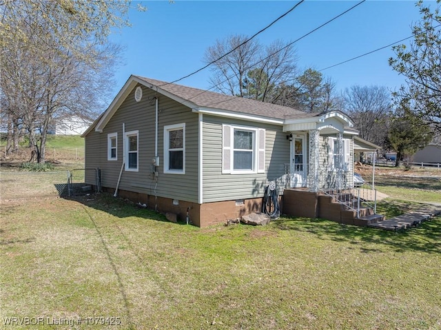 view of side of home featuring crawl space, a lawn, and roof with shingles