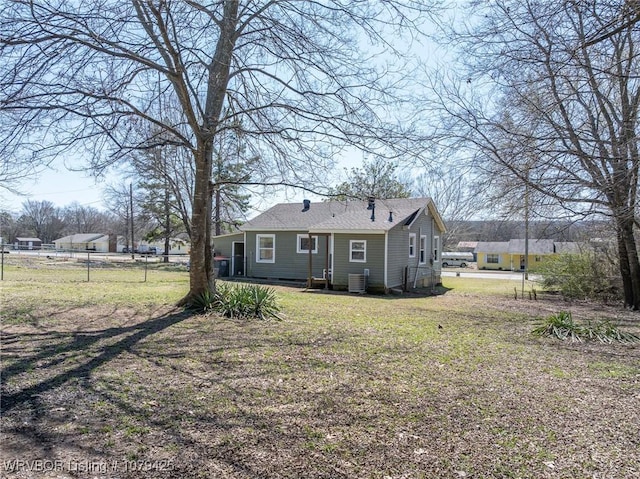 rear view of property featuring central air condition unit, a lawn, and fence