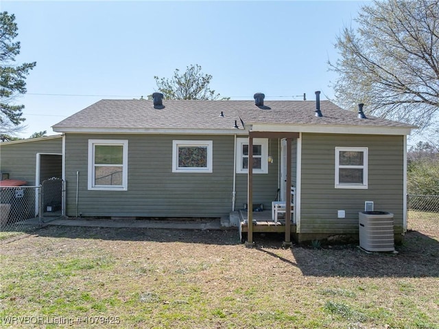 rear view of property with cooling unit, a lawn, roof with shingles, and fence