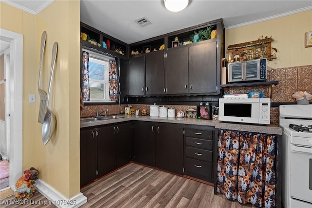 kitchen featuring white appliances, wood finished floors, ornamental molding, decorative backsplash, and a sink