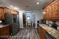 kitchen featuring brown cabinets, light countertops, refrigerator with ice dispenser, and dark wood finished floors