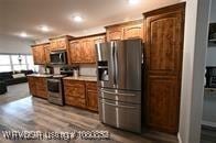 kitchen with light countertops, stainless steel appliances, brown cabinetry, and recessed lighting