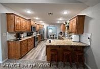 kitchen with brown cabinetry, recessed lighting, a peninsula, and stainless steel electric range