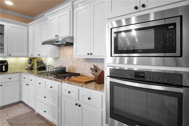 kitchen with tasteful backsplash, white cabinetry, light stone counters, and appliances with stainless steel finishes