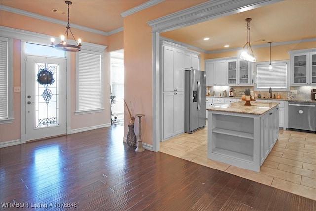 kitchen with white cabinetry, sink, stainless steel appliances, pendant lighting, and a kitchen island