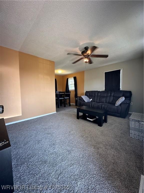 carpeted living room featuring a textured ceiling and ceiling fan