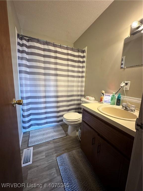 bathroom with vanity, wood-type flooring, a textured ceiling, and toilet