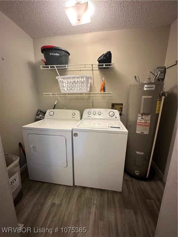 washroom with independent washer and dryer, dark wood-type flooring, electric water heater, and a textured ceiling