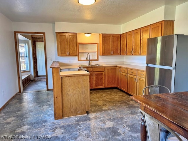 kitchen featuring sink, stainless steel fridge, and a textured ceiling