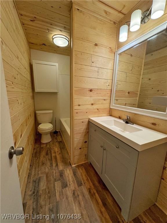 bathroom featuring wooden walls, vanity, wood-type flooring, wooden ceiling, and toilet