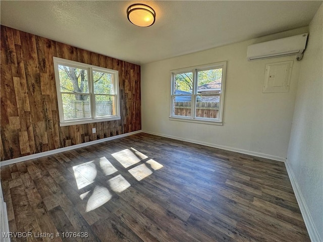 empty room with dark hardwood / wood-style floors, plenty of natural light, wooden walls, and a wall unit AC