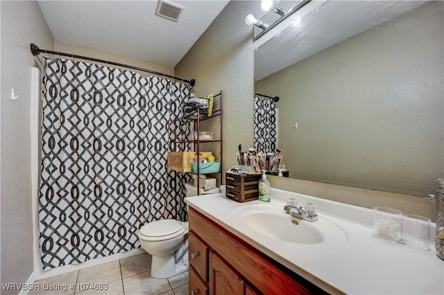 bathroom featuring tile patterned flooring, a textured ceiling, vanity, and toilet