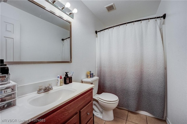 bathroom with toilet, vanity, and tile patterned floors