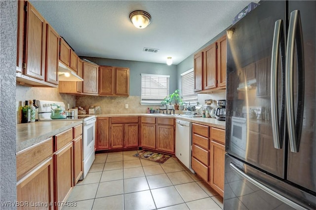 kitchen with a textured ceiling, white appliances, sink, and light tile patterned floors