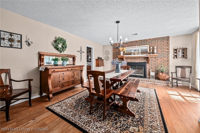 309 Neal Dr, Roland, OK 74954 - dining area with a textured ceiling, light wood-style floors, a chandelier, and a brick fireplace