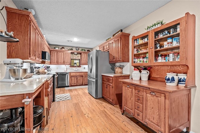 309 Neal Dr, Roland, OK 74954 - kitchen with appliances with stainless steel finishes, light countertops, a textured ceiling, light wood finished floors, and open shelves