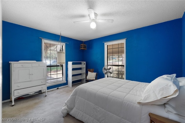 bedroom with ceiling fan, light carpet, and a textured ceiling