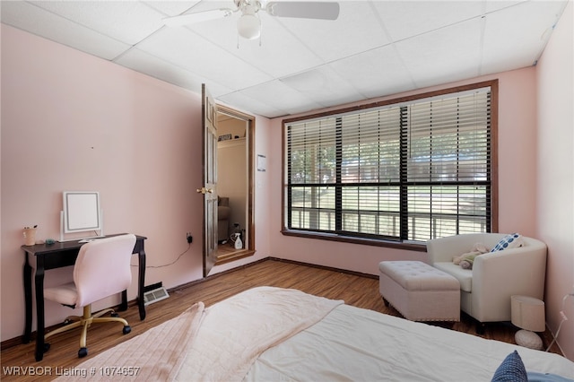 bedroom with a paneled ceiling, ceiling fan, and hardwood / wood-style flooring