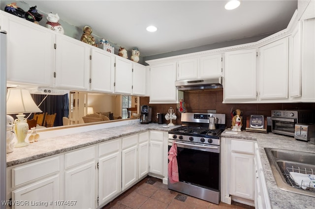 kitchen featuring backsplash, gas range, sink, and white cabinets