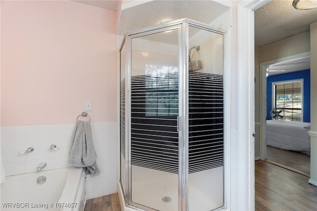 bathroom featuring hardwood / wood-style floors, separate shower and tub, and a textured ceiling