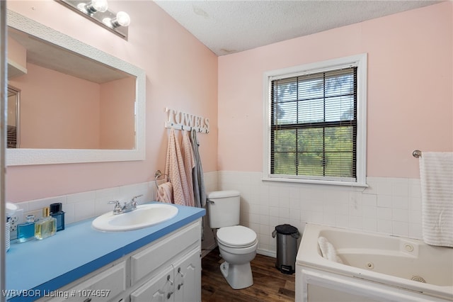 bathroom featuring a bath, a textured ceiling, toilet, vanity, and hardwood / wood-style flooring