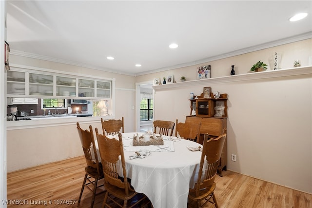 dining space with light wood-type flooring and ornamental molding