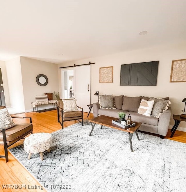 living area featuring wood finished floors, baseboards, and a barn door