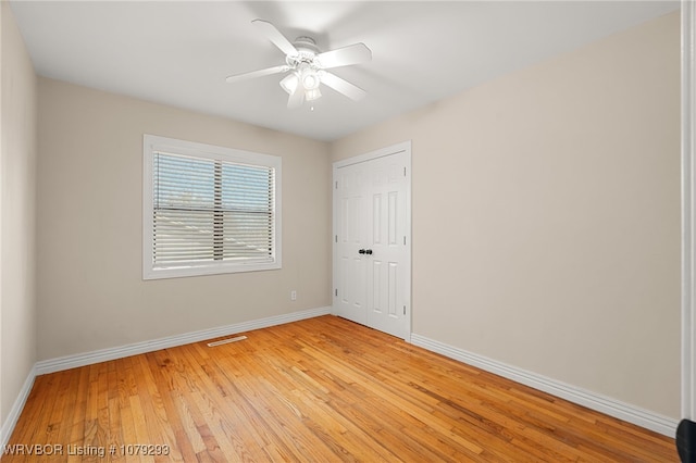 spare room with ceiling fan, light wood finished floors, and baseboards