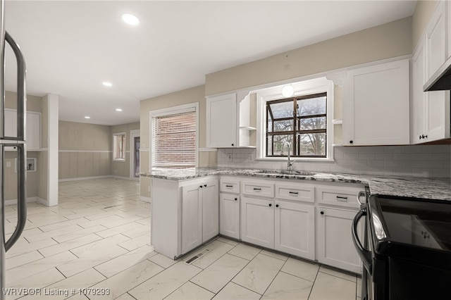 kitchen with a peninsula, black range with electric stovetop, visible vents, white cabinetry, and open shelves