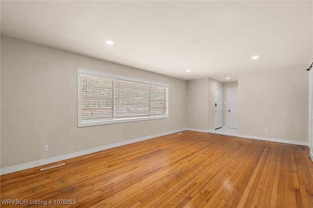 empty room with light wood-style floors, recessed lighting, visible vents, and baseboards