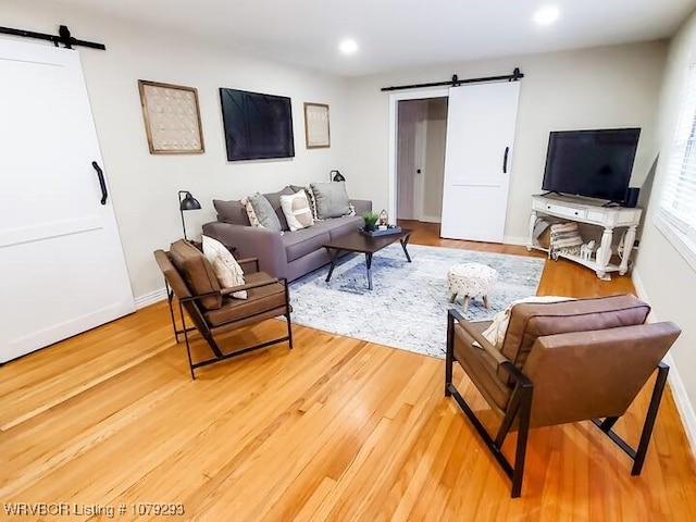 living area featuring recessed lighting, baseboards, light wood finished floors, and a barn door