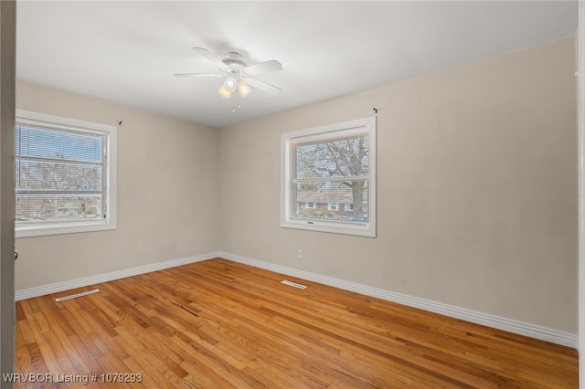 empty room with visible vents, plenty of natural light, light wood-style flooring, and baseboards