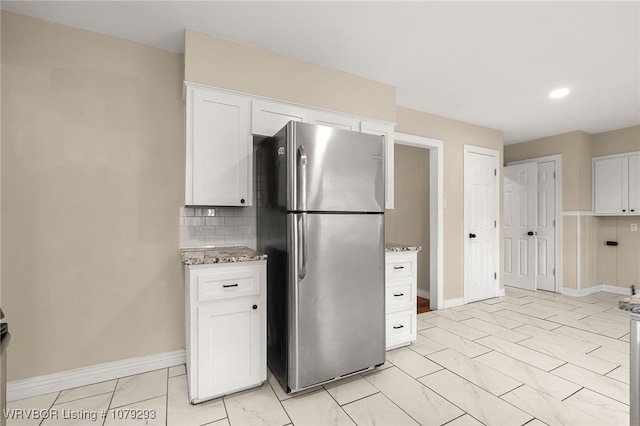 kitchen with marble finish floor, tasteful backsplash, freestanding refrigerator, white cabinets, and light stone countertops