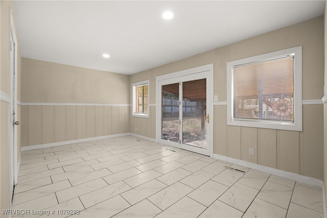 spare room featuring recessed lighting, marble finish floor, and wainscoting