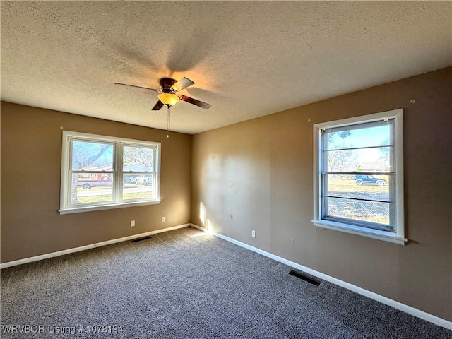 carpeted spare room featuring plenty of natural light, ceiling fan, and a textured ceiling