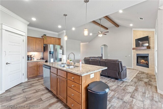 1228 Bradley St, Centerton, AR 72719 - kitchen with stainless steel appliances, open floor plan, brown cabinetry, arched walkways, and light wood-style floors