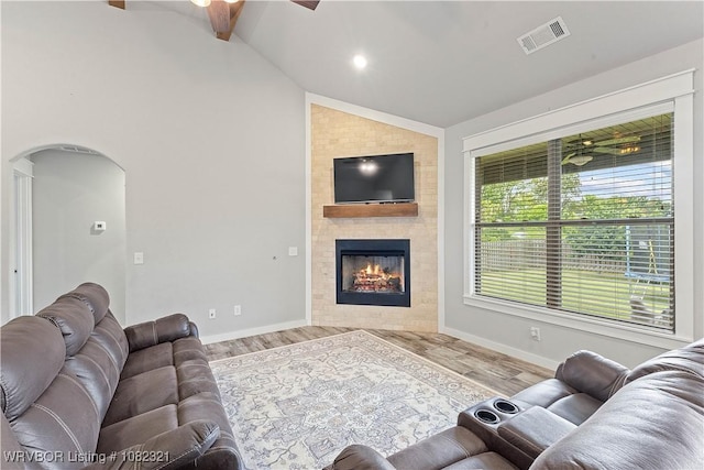 1228 Bradley St, Centerton, AR 72719 - living room featuring ceiling fan, vaulted ceiling, wood finished floors, arched walkways, and a large fireplace