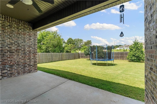 1228 Bradley St, Centerton, AR 72719 - fenced backyard with a trampoline, a ceiling fan, and a patio