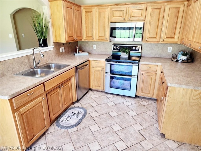 kitchen featuring kitchen peninsula, backsplash, stainless steel appliances, and sink