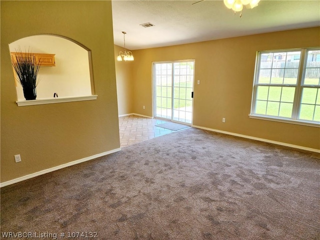 carpeted empty room with ceiling fan with notable chandelier