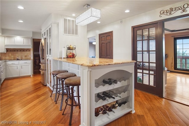 3417 Royal Scots Way, Fort Smith, AR 72908 - kitchen with light wood finished floors, a breakfast bar area, white cabinetry, light stone countertops, and backsplash