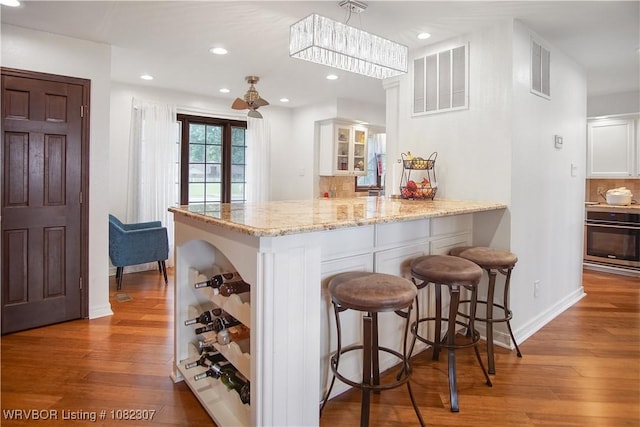 3417 Royal Scots Way, Fort Smith, AR 72908 - kitchen featuring oven, wood-type flooring, a peninsula, light stone counters, and recessed lighting