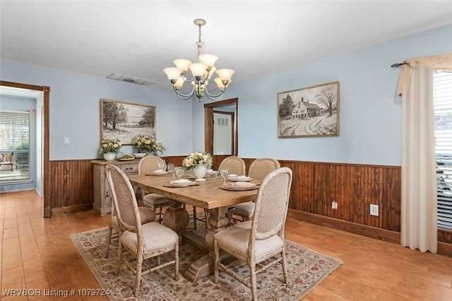 2702 Rambo Cir, Lavaca, AR 72941 - dining area featuring a wainscoted wall, wooden walls, light wood-style flooring, and a chandelier